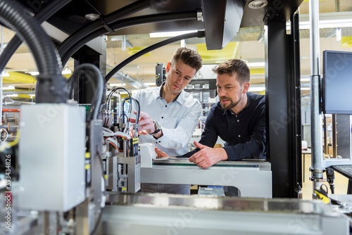 Two men examining machine in factory photo