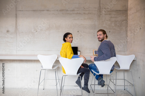 Young man and woman using moblie devices in concrete room photo