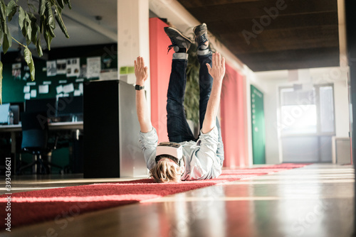 Businessman lying on carpet on the floor wearing VR glasses exercising
