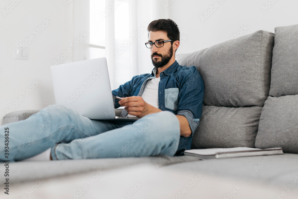 Man using laptop, working on the couch at home Man using laptop, working on the couch at home