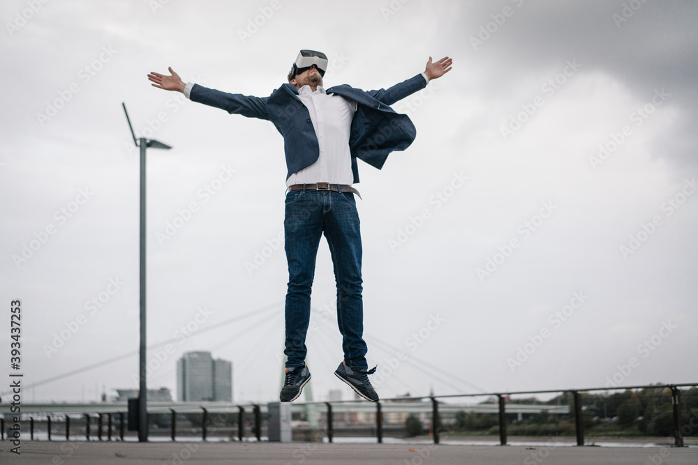 Businessman wearing VR glasses jumping in the city Businessman wearing VR glasses jumping in the city