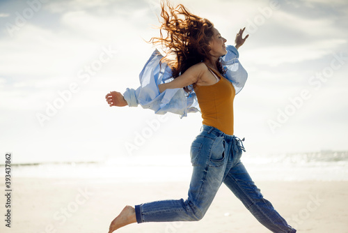 Happy woman having fun at the beach, jumping in the air photo