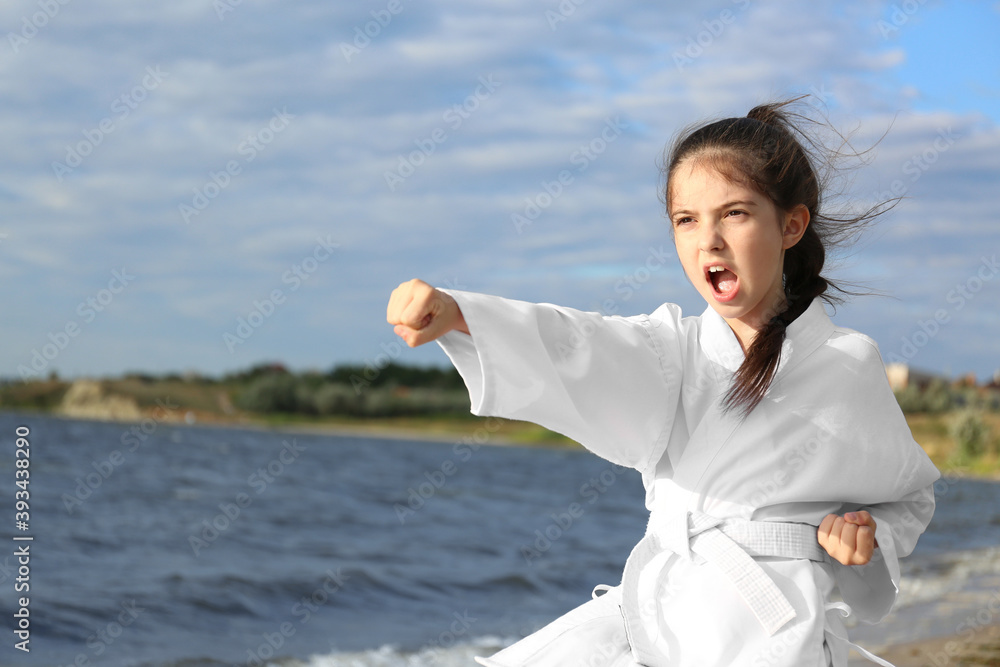Cute little girl in kimono practicing karate near river Cute little girl in kimono practicing karate near river
