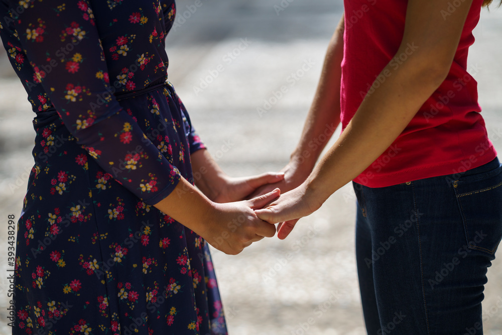 Women holding hands while standing on footpath at park Women holding hands while standing on footpath at park