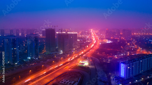 Aerial view of the night city and the road in the fog.