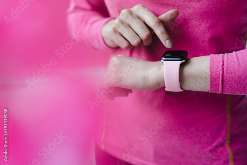 Close-up of woman in pink sportswear adjusting her smartwatch photo