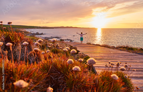 Italy, Sardinia, Lu Litarroni, senior woman on wooden boardwalk at sunset
