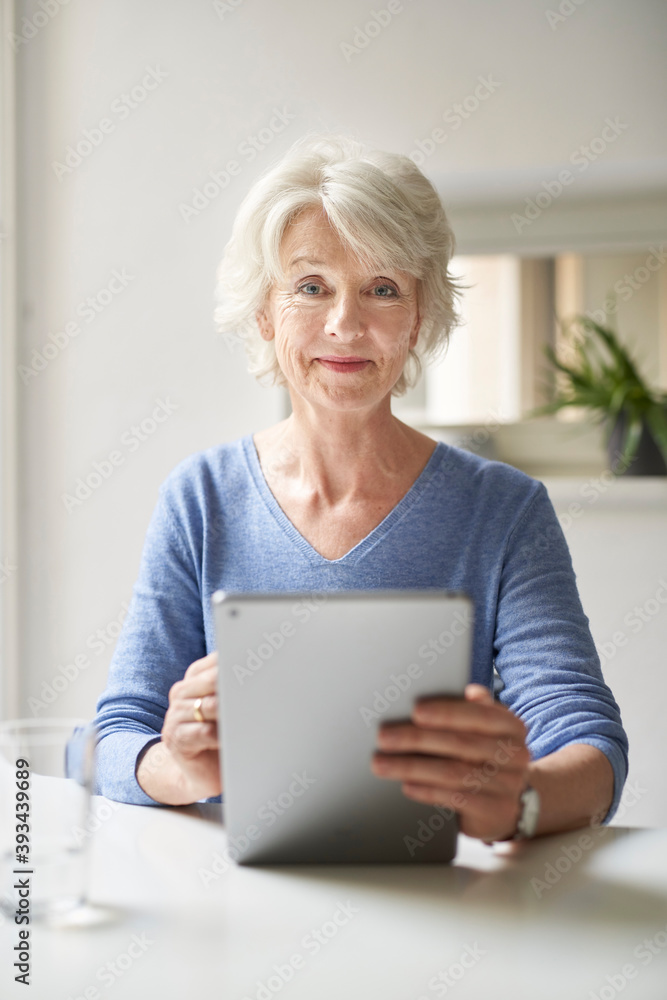 Portrait of smiling mature woman using digital tablet at desk Portrait of smiling mature woman using digital tablet at desk