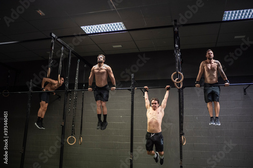 Athletes doing pull ups exercise on rod at gym photo