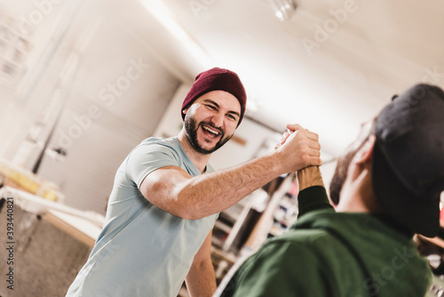 Two happy young men high fiving in workshop photo