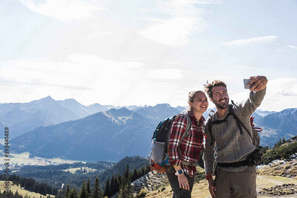 Austria, Tyrol, smiling young couple taking a selfie in mountainscape Austria, Tyrol, smiling young couple taking a selfie in mountainscape