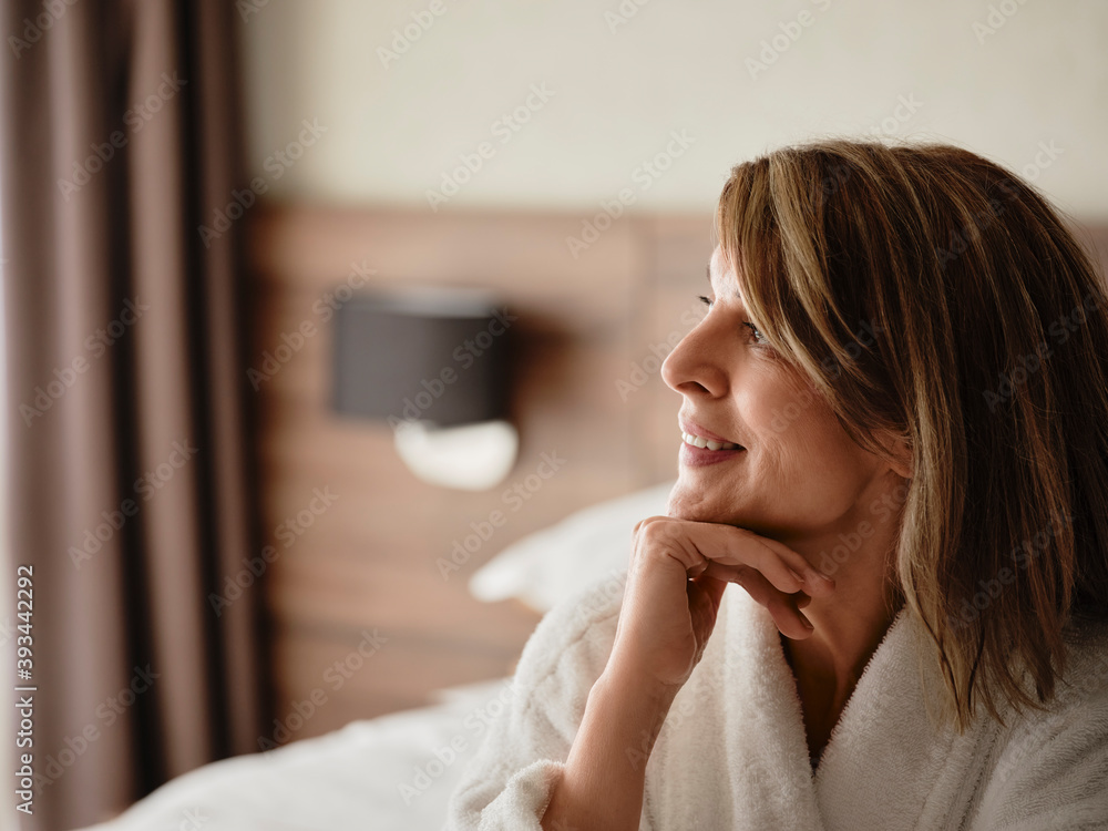 Thoughtful smiling blond woman looking away while sitting in hotel room Thoughtful smiling blond woman looking away while sitting in hotel room