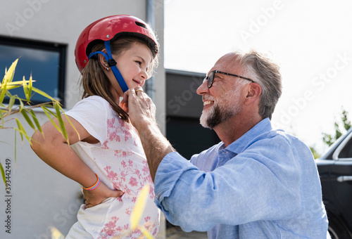 Mature man fixing safety helmet on little girl's head photo