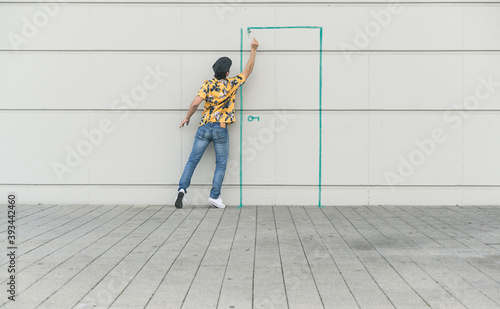 Digital composite of young man drawing a door at a wall photo