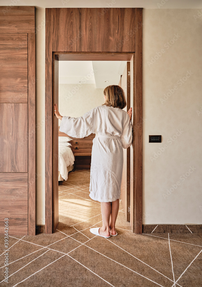 Senior woman in bathrobe standing at hotel room doorway Senior woman in bathrobe standing at hotel room doorway