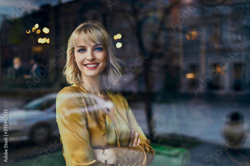 Portrait of smiling elegant woman behind windowpane