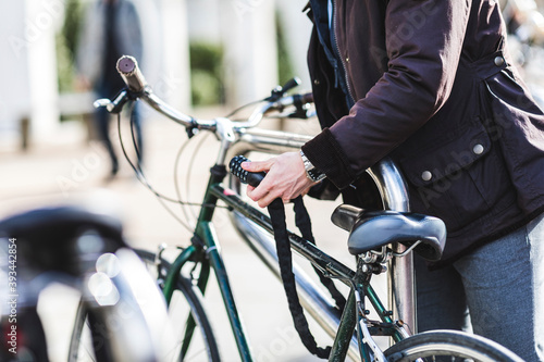 Businessman locking bicycle in the city, partial view