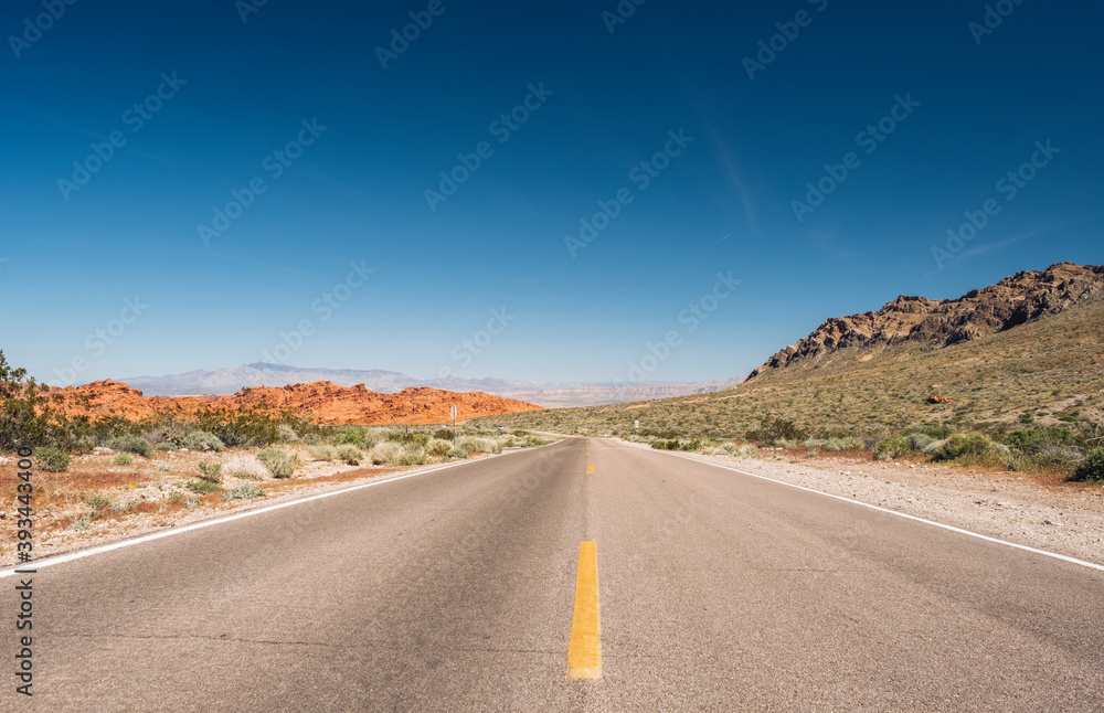 Diminishing view of empty desert road against blue sky, Nevada, USA Diminishing view of empty desert road against blue sky, Nevada, USA