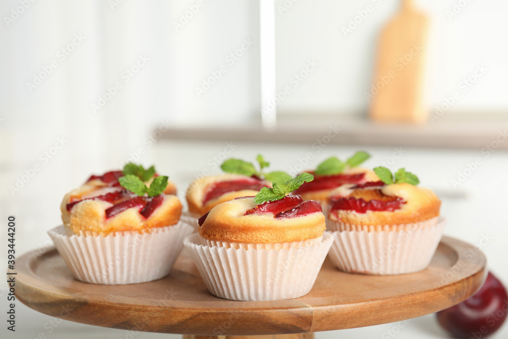 Delicious sweet cupcakes with plums on wooden stand, closeup Delicious sweet cupcakes with plums on wooden stand, closeup