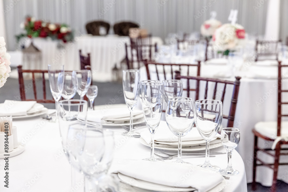 Fototapeta premium Fancy table set for dinner with napkin glasses in restaurant, luxury interior background. Wedding elegant banquet decoration and items for food arranged by catering service on white tablecloth table.