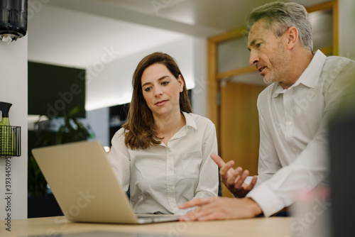 Businessman using laptop while having discussion in office
