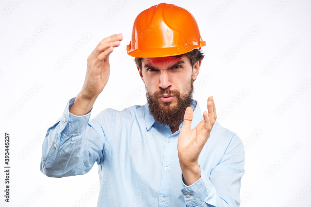 A man in a working uniform orange hard hat gestures with his hands emotions Construction engineer Professional