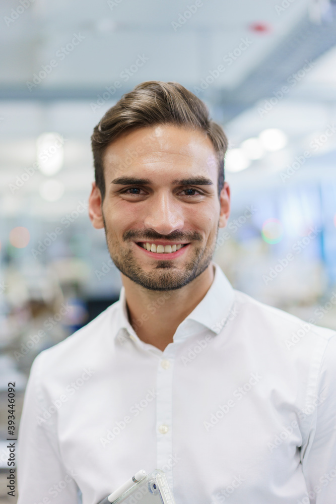 Smiling young male engineer standing at illuminated factory Smiling young male engineer standing at illuminated factory