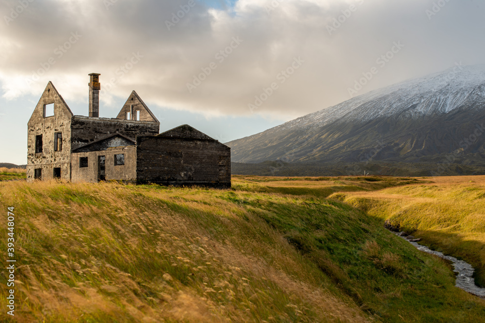 Building ruins against a snow covered mountain backdrop in Iceland Building ruins against a snow covered mountain backdrop in Iceland