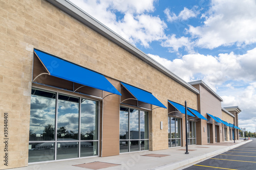 Brand new no logo, signage or label storefront of a under construction strip mall in the USA with blue awnings above the entrance, blue cloudy sky reflecting on the windows photo