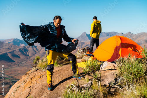 Male hikers coordinating the camp near tent on mountain peak photo