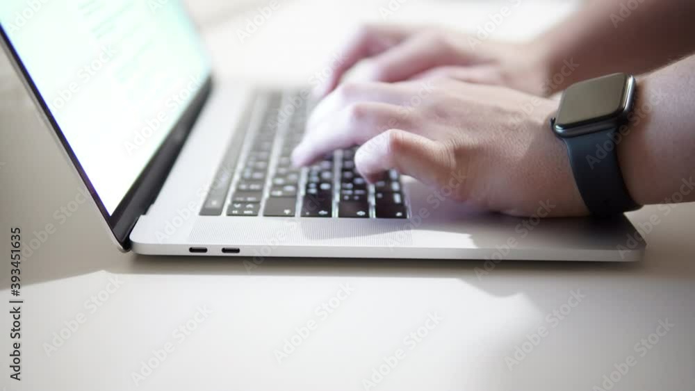 Men's hands with a smart watch on the wrist print text, code on the keyboard of the laptop. Men's hands with a smart watch on the wrist print text, code on the keyboard of the laptop.