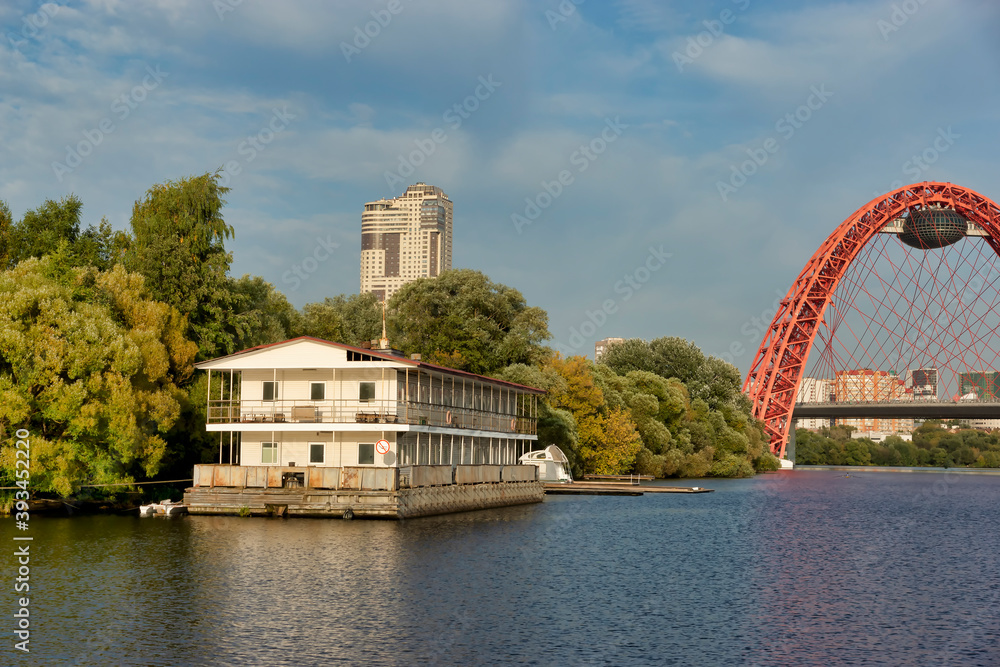 Moscow, Russia - September 24, 2020: Floating house on the river. Zhivopisny bridge across the Moscow river