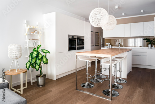 Modern dining room with two pendant lamps over dining table, chairs and oven