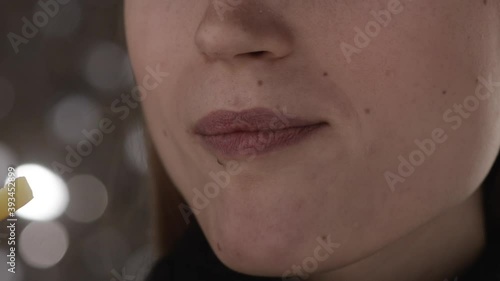 Close-up young european positive girl bites off a slice of mango smiling and chewing. Concept of eating fruit and healthy food. Slow motion
