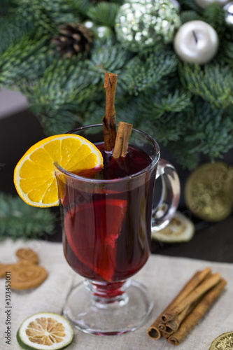 winter treats, a mug of warm wine with an orange, and cookies, ingredients on a wooden brown table. Traditional hot drink for Christmas, in the background Christmas composition