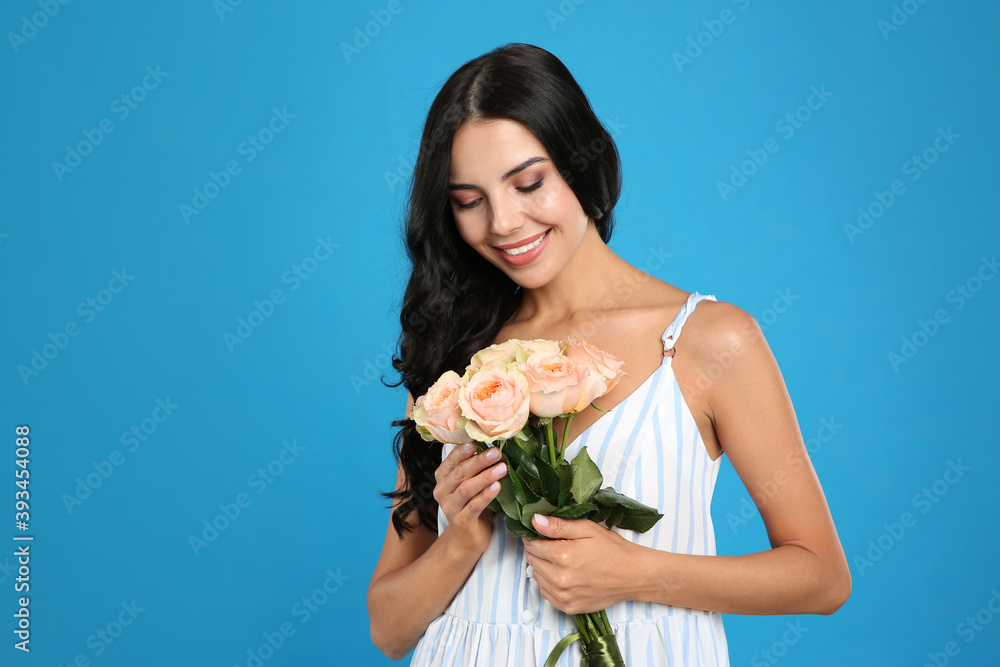 Portrait of smiling woman with beautiful bouquet on light blue background Portrait of smiling woman with beautiful bouquet on light blue background
