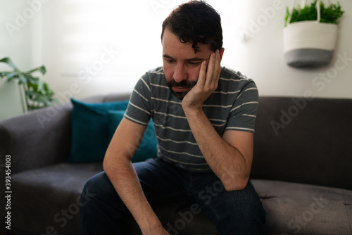 Depressed adult man sitting on the couch © AntonioDiaz