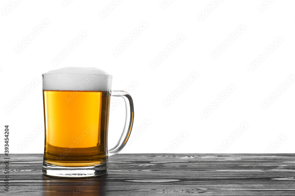 Glass mug of tasty beer on black wooden table against white background Glass mug of tasty beer on black wooden table against white background