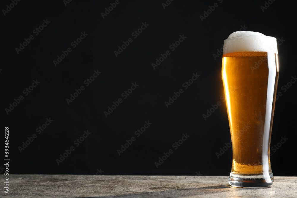 Cold tasty beer on grey table against dark background. Space for text