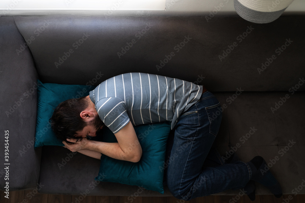 Man in his 30s weeping on the couch