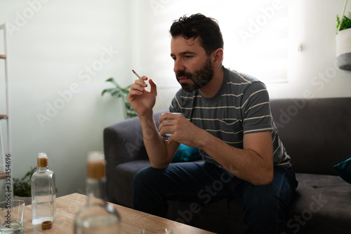 Alcoholic latin man smoking and drinking alone