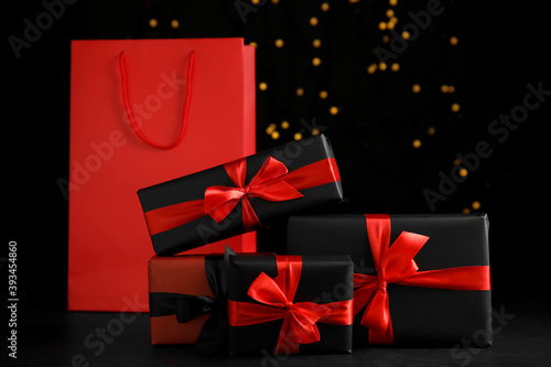 Gift boxes and paper shopping bag against blurred lights. Black Friday sale