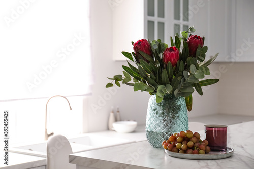 Bouquet with beautiful protea flowers on table in kitchen, space for text. Interior design