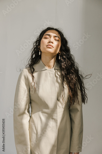 young woman with eyes closed standing in the sun