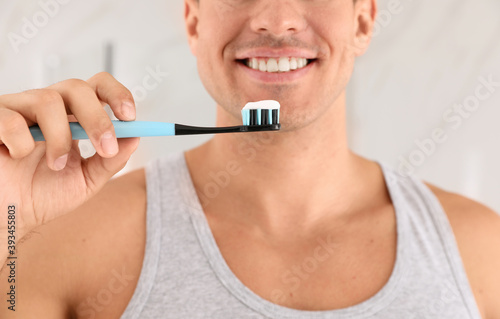 Man holding toothbrush with paste indoors  closeup