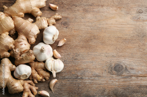 Ginger and fresh garlic on wooden table, flat lay with space for text. Natural cold remedies