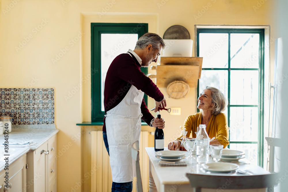 Cheerful adult couple preparing for romantic dinner Cheerful adult couple preparing for romantic dinner