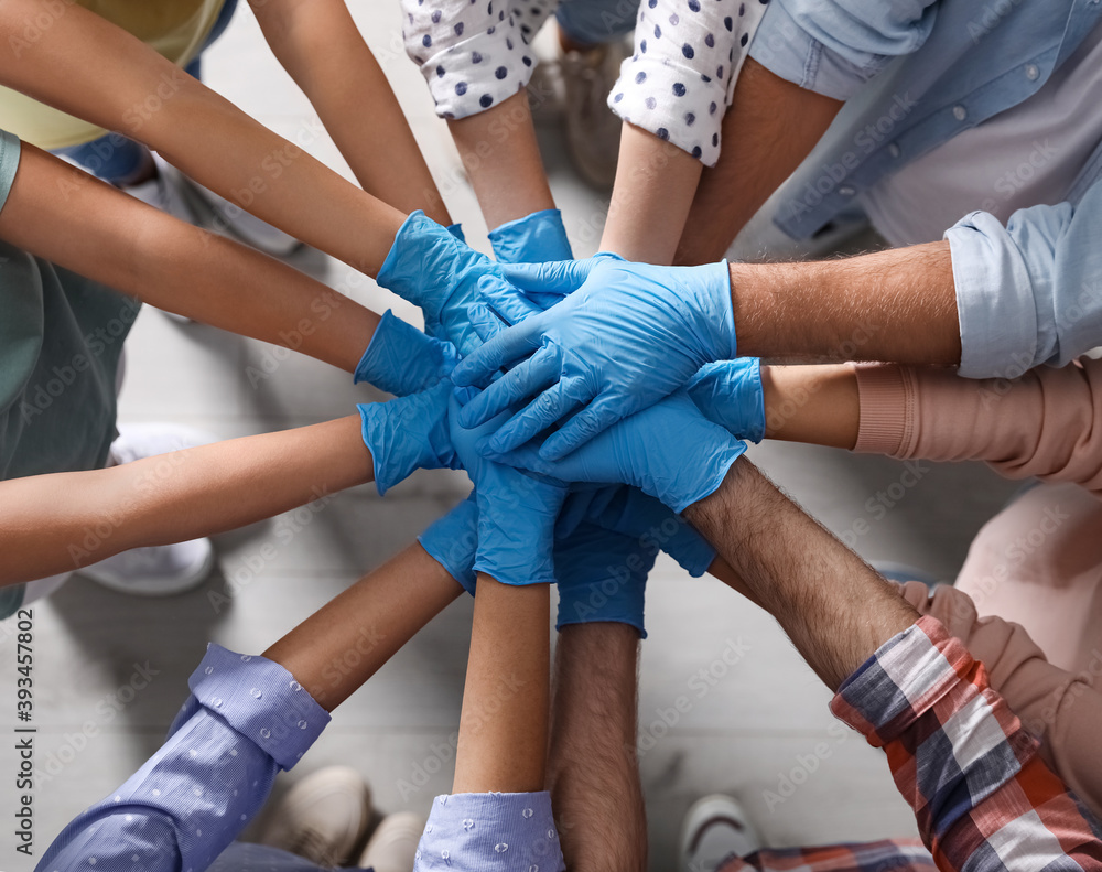 People in blue medical gloves stacking hands indoors, top view People in blue medical gloves stacking hands indoors, top view