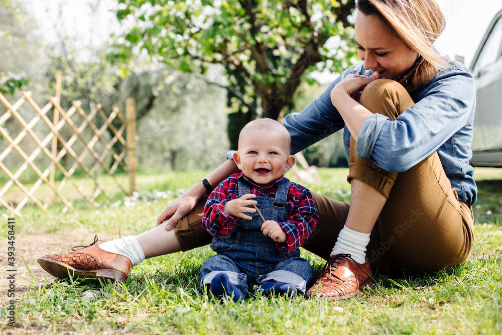 Happy mother and baby sitting on grass in yard Happy mother and baby sitting on grass in yard