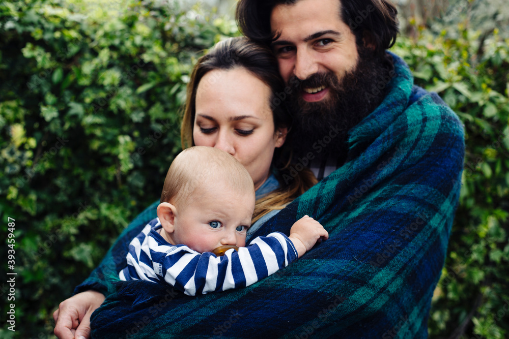 Young parents and baby with blanket in garden Young parents and baby with blanket in garden